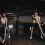Two people engage in a powerful indoor battle rope workout, showcasing strength and energy.