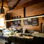 Warm café ambiance with vintage light bulbs and a blurred background of a counter and menu.